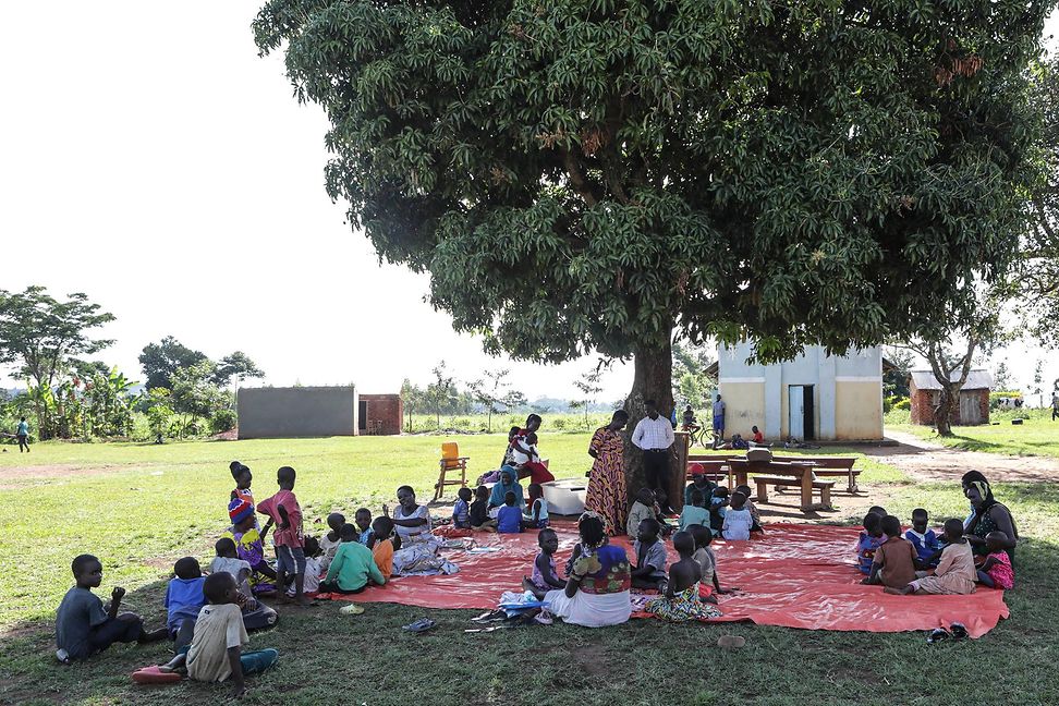 Kinder und Freiwillige beim Spiel unter dem Baum