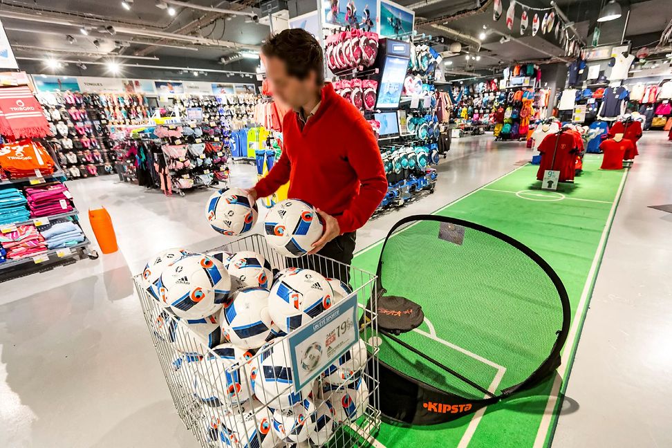 A man is playing with footballs in a sports shop