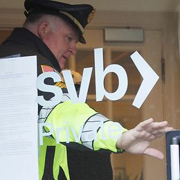 A police officer holds the door open for a customer at a branch of Silicon Valley Bank following the bank's collapse