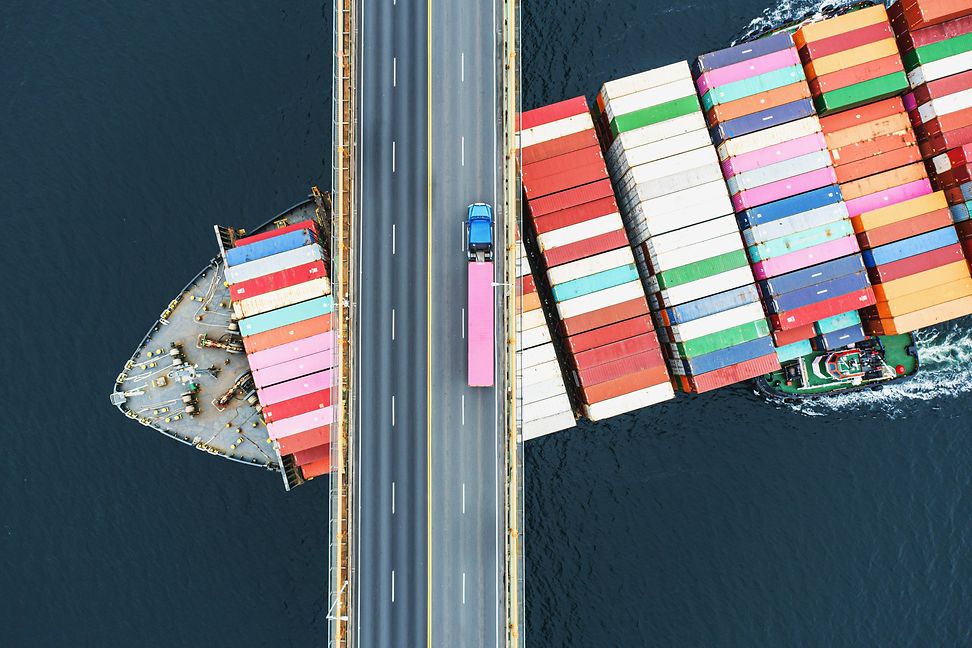 Containerschiff unter Brücke mit LKW