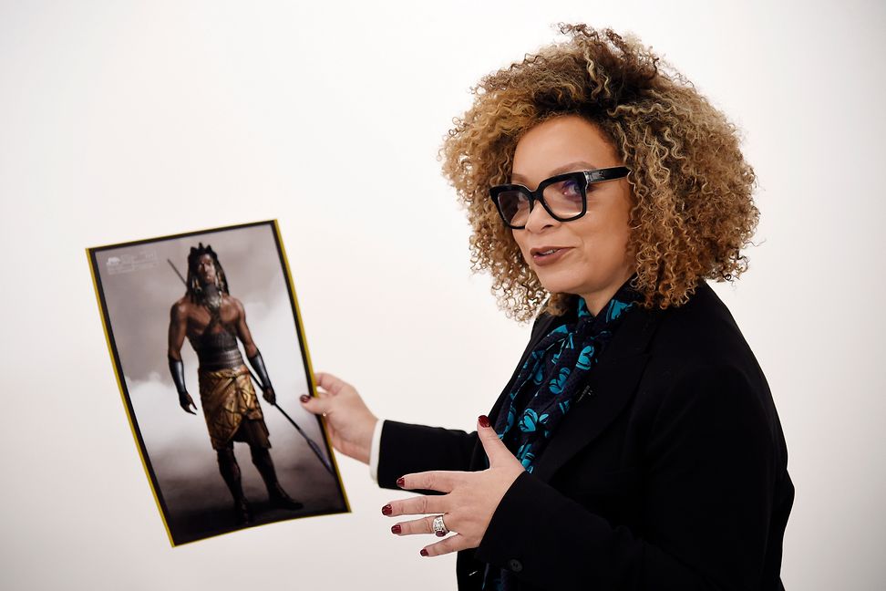 Ruth E. Carter is holding a photo of one of her designs 