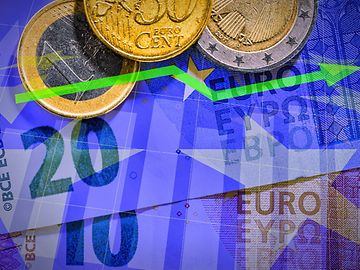 Euro banknotes and coins against an upward-pointing chart