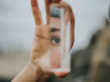 Frau schaut in eine Spiegelscherbe