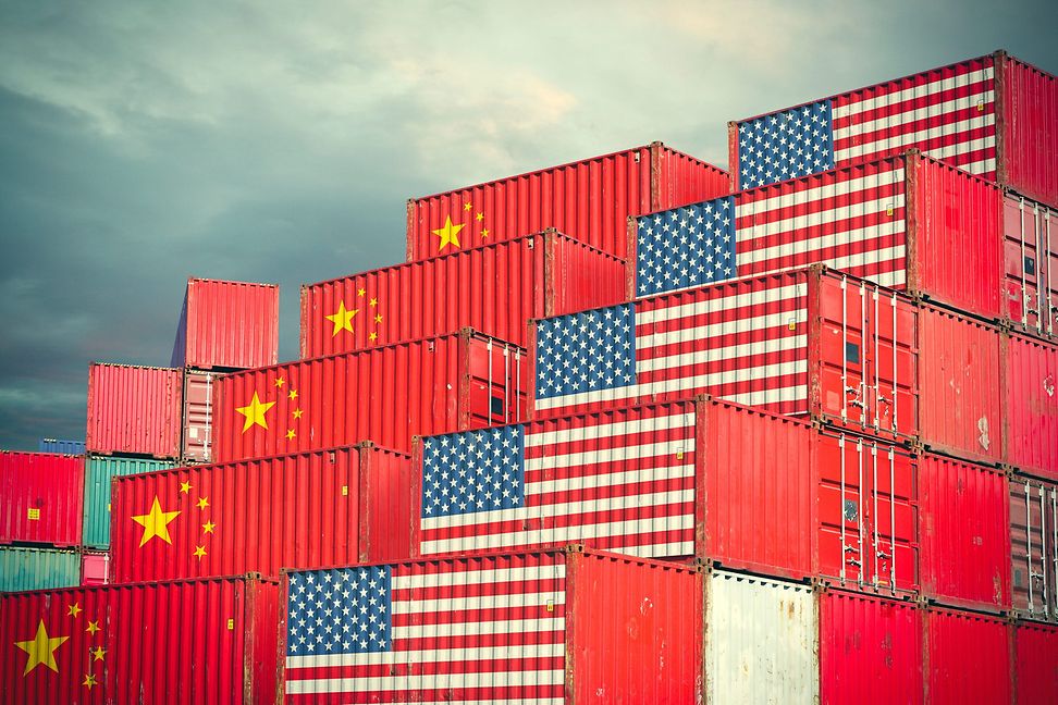 Freight containers in a port, half painted with the US flag and half with the Chinese flag