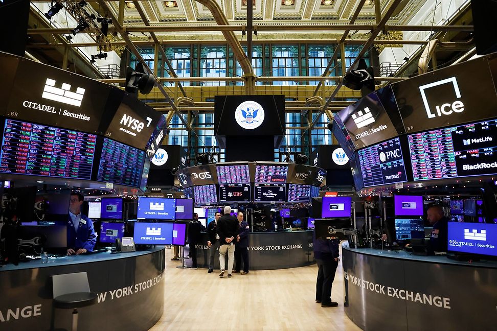 Traders in the trading room of a stock exchange, surrounded by screens showing stock market prices.