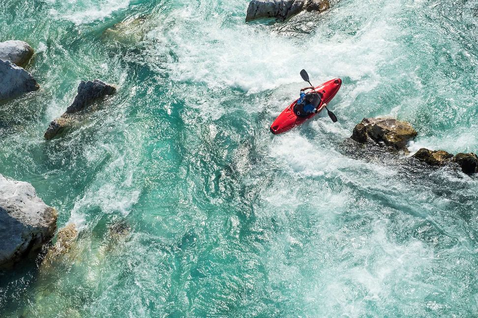 Bird's eye view of a red kayak navigating rocks and whitewater