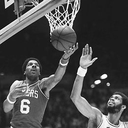 Two basketball players battle for the ball in front of the basket. The picture quality shows that the image is not digital.
