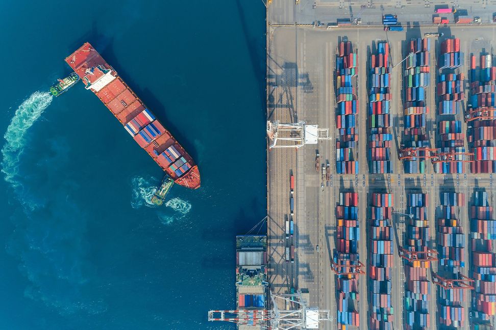 Hafenschiff beim Manövrieren im Containerhafen, Vogelperspektive