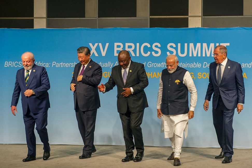 Fünf Männer stehen vor einem Plakat mit der Aufschrift "BRICS Summit".