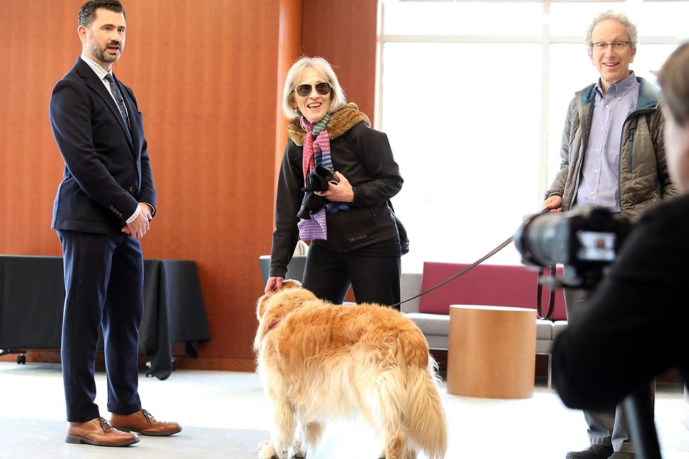 A woman and a man with a golden retriever arrive at an event.