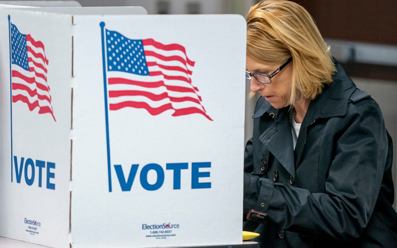 A woman at a polling station with a US flag