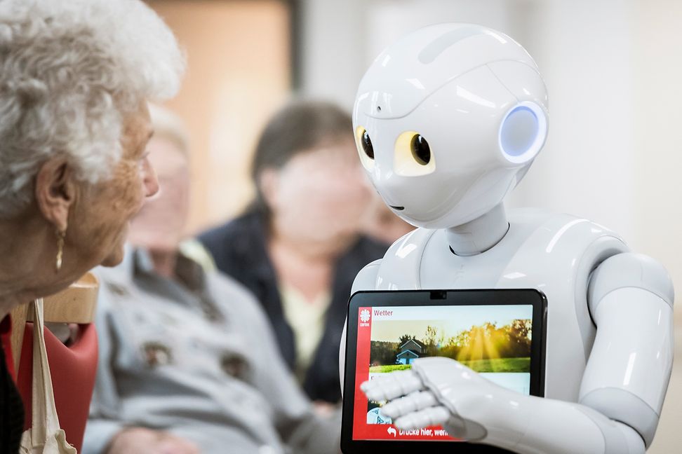 A senior citizen interacts with a robot