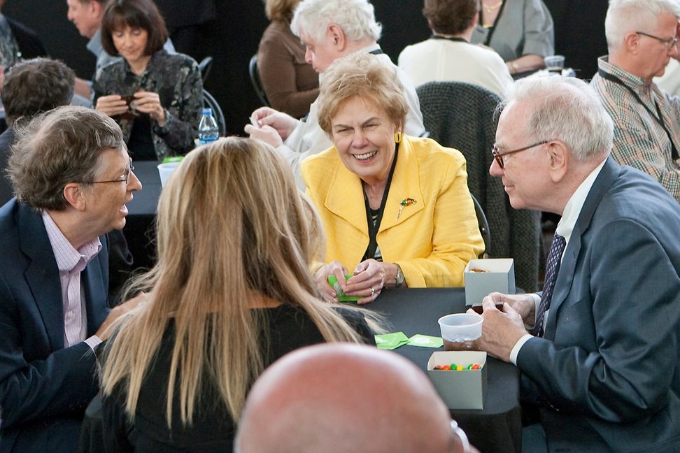 Vier Personen spielen Karten an einem Tisch und lachen.