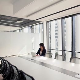 Einzelne Mitarbeiterin in modern eingerichtetem Sitzungszimmer