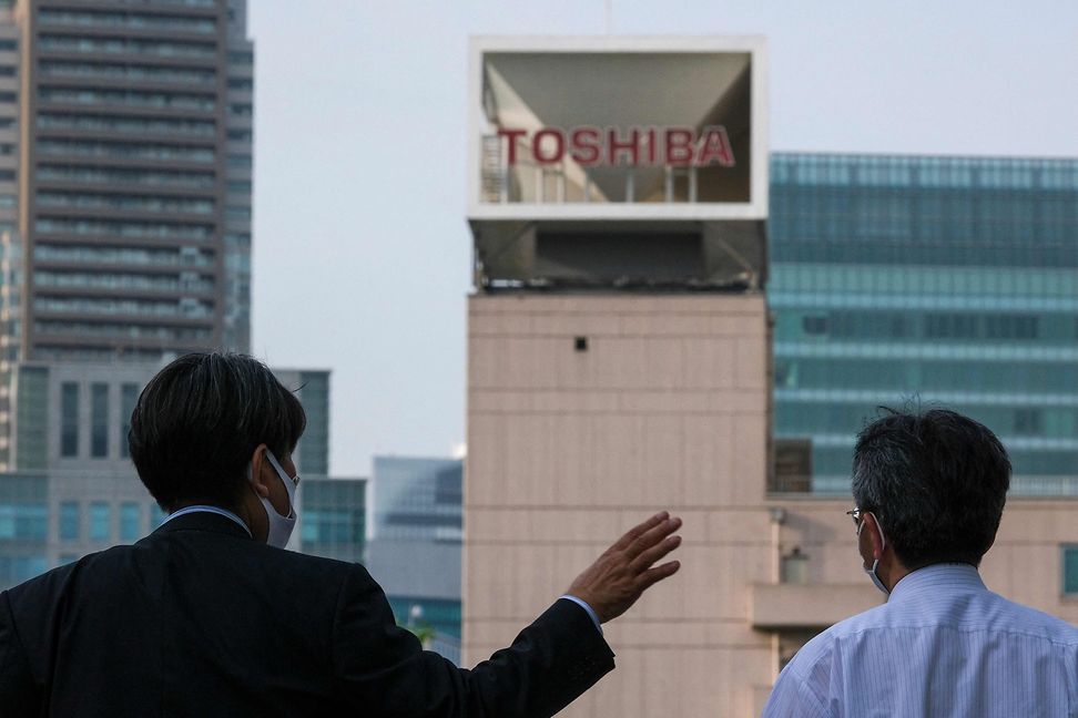 Two people in front of a high-rise building with Toshiba written on it