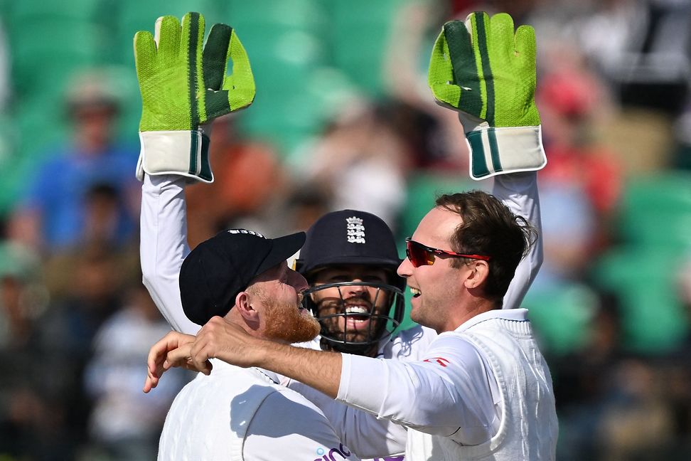 Three British cricketers celebrate on the field.