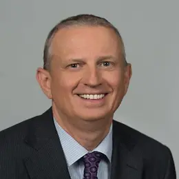 A man in a suit and tie is smiling into the camera.